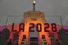 FILE - An LA 2028 sign is seen in front of the Olympic cauldron at the Los Angeles Memorial Coliseum, Wednesday, Sept. 13, 2017. The 2028 Los Angeles Olympics have announced more venue assignments, with the cities of Carson and Long Beach reprising their roles from previous games held in the region. (AP Photo/Richard Vogel, File)