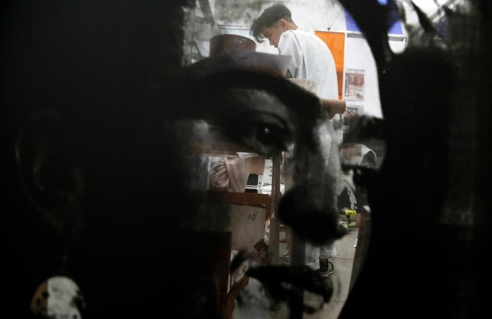 FILE - An artist screen prints Frida Kahlo's face in the background of an installation piece by Rirkrit Tiravanija and Thomas Vu at the Untitled art gallery during Art Basel in Miami Beach, Florida, Dec. 6, 2018. The 70th anniversary of Kahlo's death will be July 13, 2024. (AP Photo/Bryn Anderson, File)