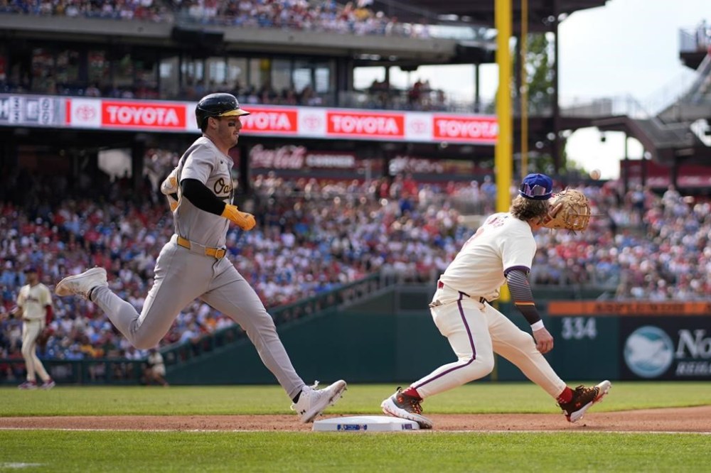 Oakland Athletics' Brent Rooker reaches first for a single past Philadelphia Phillies first baseman Bryce Harper during the fourth inning of a baseball game, Saturday, July 13, 2024, in Philadelphia. (AP Photo/Matt Slocum)