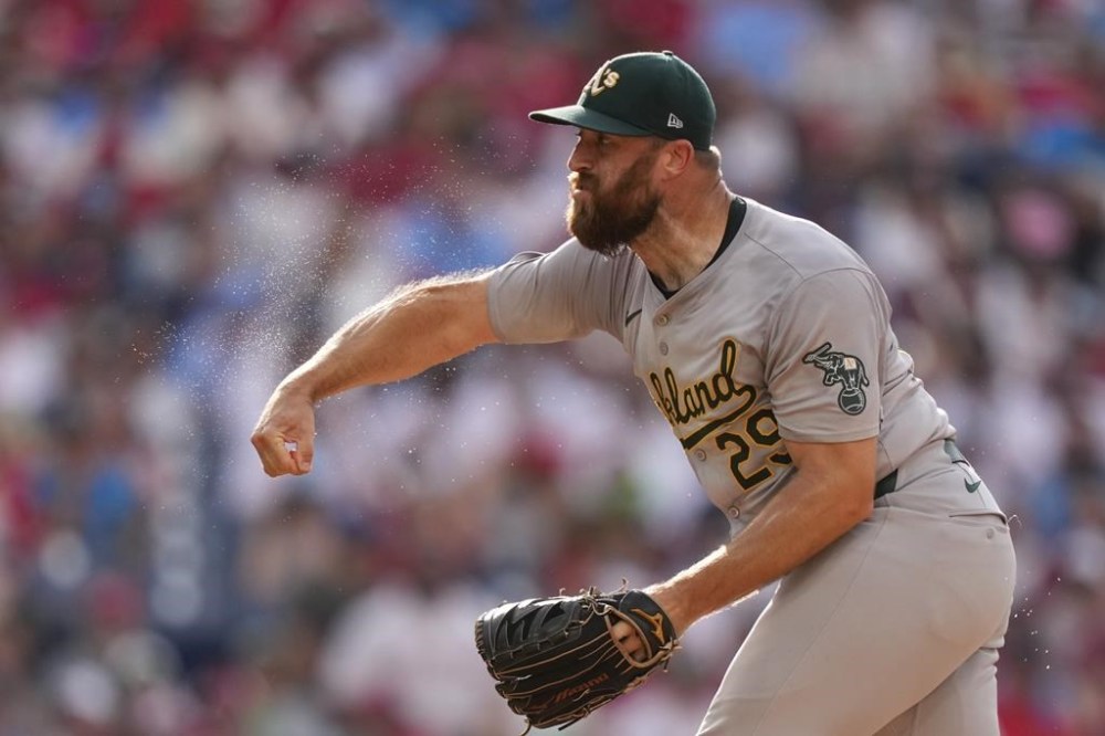 Sweat flies off the arm of Oakland Athletics' Austin Adams as he pitches during the seventh inning of a baseball game against the Philadelphia Phillies, Saturday, July 13, 2024, in Philadelphia. (AP Photo/Matt Slocum)