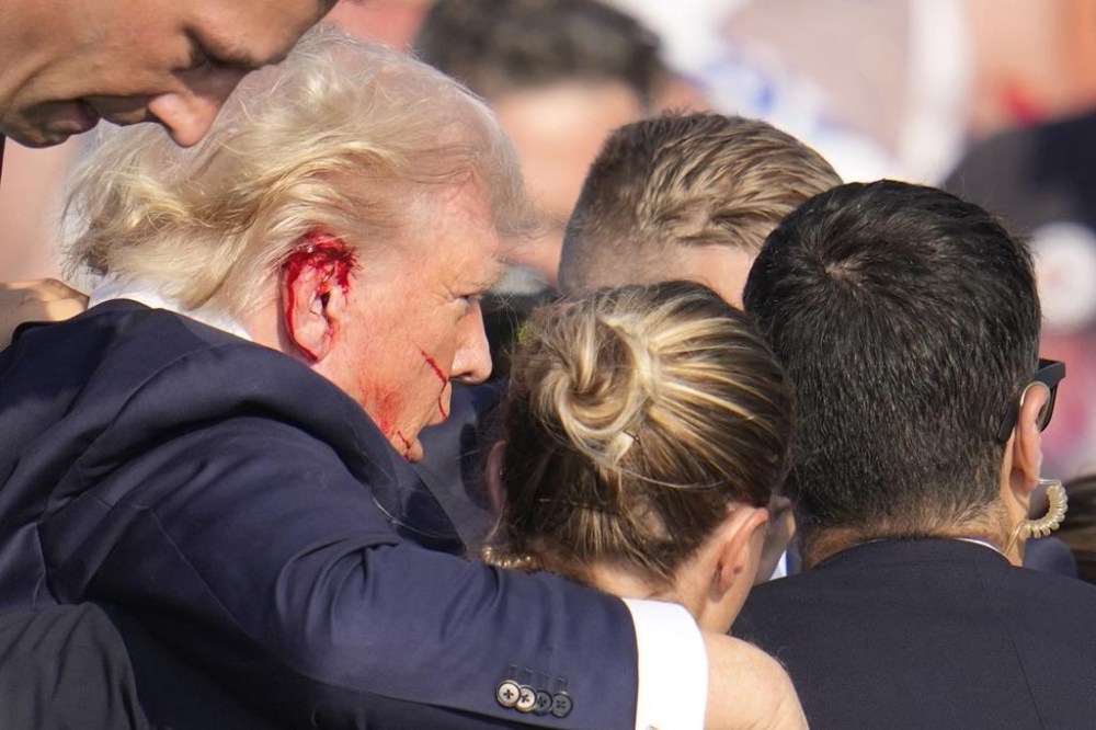Republican presidential candidate former President Donald Trump is surround by U.S. Secret Service agents as he is helped off the stage at a campaign rally in Butler, Pa., Saturday, July 13, 2024. (AP Photo/Gene J. Puskar)