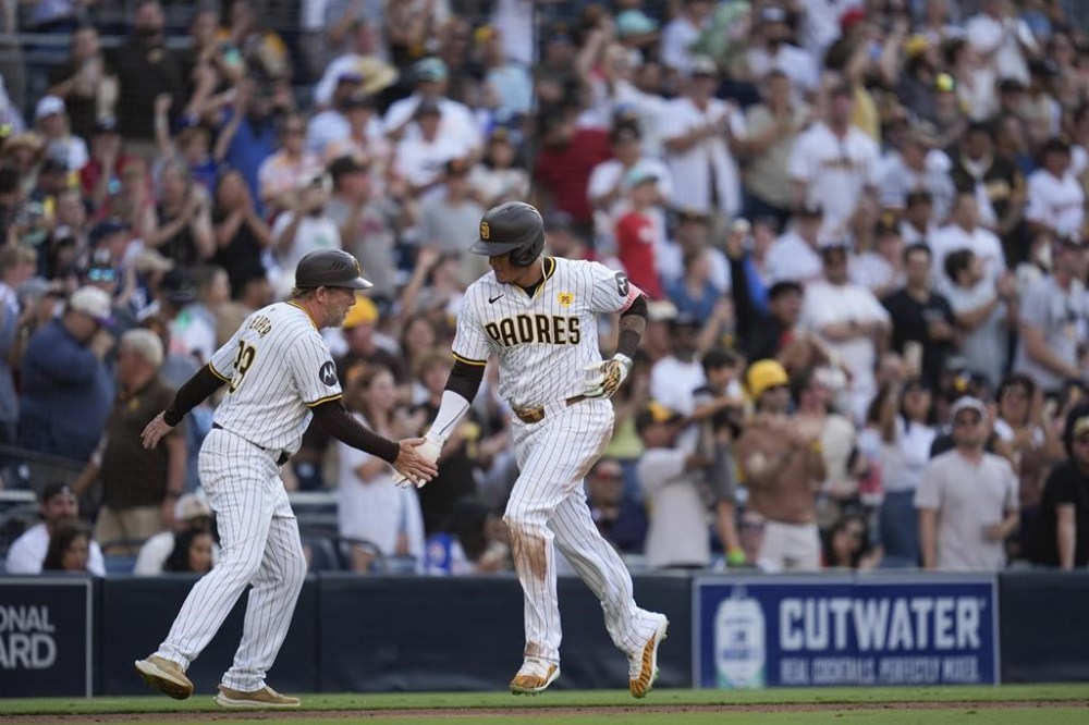San Diego Padres' Manny Machado, right, celebrates with third base coach Tim Leiper after hitting a home run during the eighth inning of a baseball game against the Atlanta Braves, Saturday, July 13, 2024, in San Diego. (AP Photo/Gregory Bull)