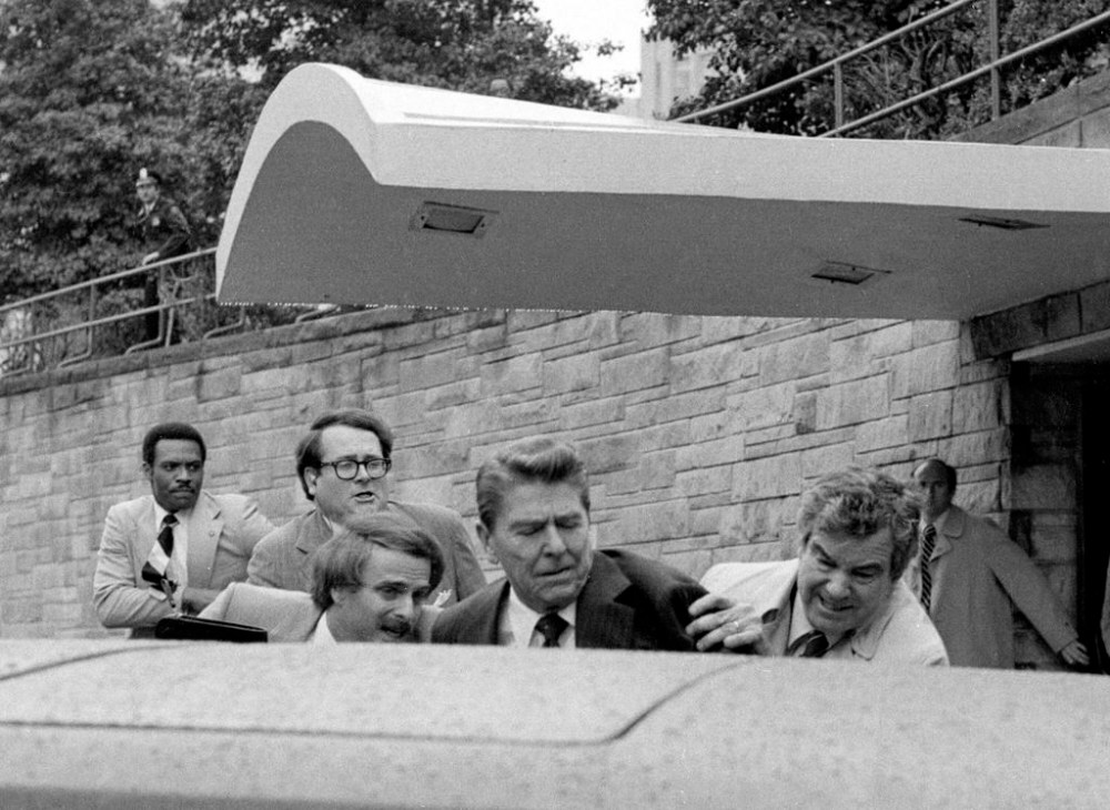 FILE - President Ronald Reagan waves and then looks up before being shoved into the President's limousine by secret service agents after being shot outside a Washington hotel, March 30, 1981. The assassination attempt of former President Donald Trump has parallels to the last time a president or presidential candidate was wounded — in 1981 when Ronald Reagan was nearly killed by an assailant's bullet. Reagan's life was spared thanks to the quick actions of a Secret Service agent and the skill of doctors and nurses at a Washington, D.C., hospital. (AP Photo/Ron Edmonds, File)