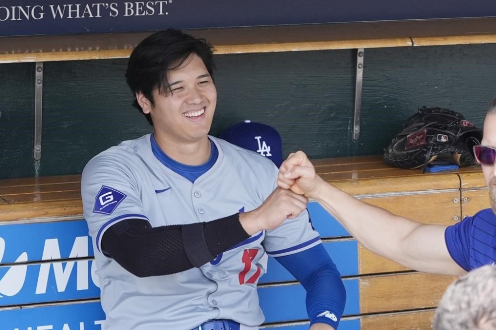 Los Angeles Dodgers designated hitter Shohei Ohtani fist bumps a member of the team in the dugout before the first inning of a baseball game against the Detroit Tigers, Sunday, July 14, 2024, in Detroit. (AP Photo/Carlos Osorio)