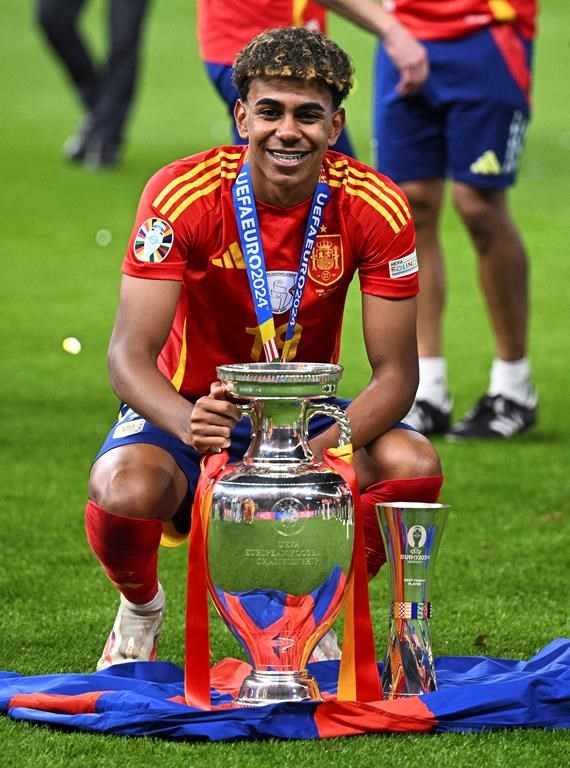 Spain's Lamine Yamal poses with the trophy after the final match against England at the Euro 2024 soccer tournament in Berlin, Germany, Sunday, July 14, 2024. Spain won the game 2-1. (Tom Weller/dpa via AP)