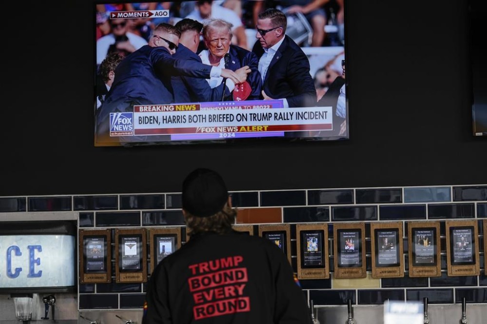 A person watches news in a local bar near the Fiserv Forum watching news ahead of the 2024 Republican National Convention, Saturday, July 13, 2024, in Milwaukee. THE CANADIAN PRESS/AP, Matt Rourke