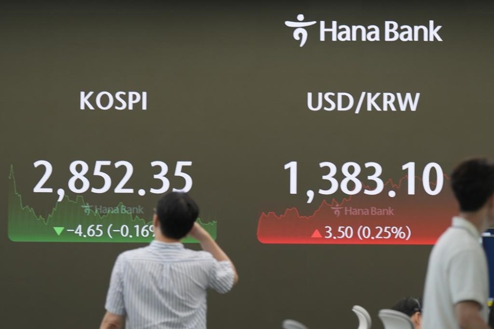 A currency trader walks near the screen showing the Korea Composite Stock Price Index (KOSPI), left, and the foreign exchange rate between U.S. dollar and South Korean won at a foreign exchange dealing room in Seoul, South Korea, Monday, July 15, 2024. Asian shares began the week trading mixed as China reported that its economy expanded at a slower-than-forecast 4.7% annual pace in the last quarter. (AP Photo/Lee Jin-man)