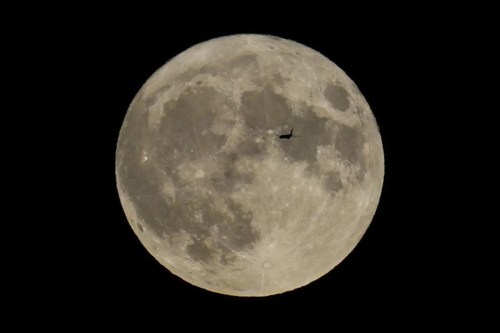FILE - A plane passes in front of the moon, Aug. 30, 2023, in Chicago. Scientists have confirmed a cave on the moon, not far from where Neil Armstrong and Buzz Aldrin landed 55 years ago this week, and suspect there are hundreds more that could house future astronauts. (AP Photo/Kiichiro Sato, file)