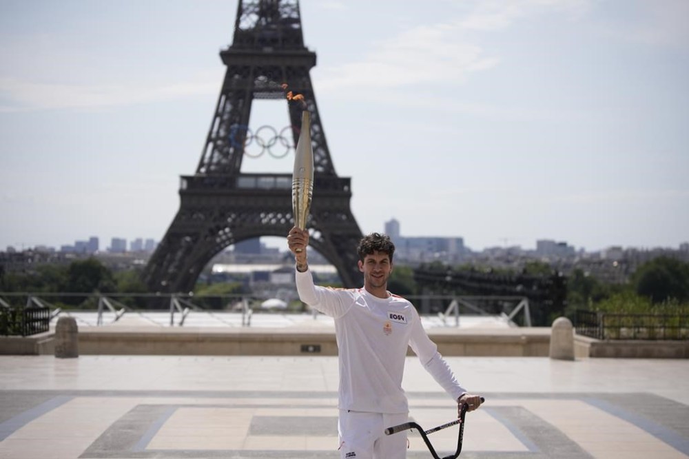 French BMX champion Matthias Dandois holds the Olympic torch in front of the Eiffel Tower, Monday, July 15, 2024 in Paris, just 11 days before the French capital hosts exceptionally ambitious and high-security Paris Olympic Games. (AP Photo/Louise Delmotte)