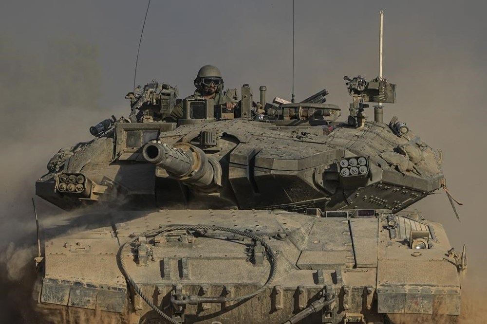 An Israeli soldier moves on the top of a tank near the Israeli-Gaza border, as seen from southern Israel, Sunday, July 14, 2024. (AP Photo/Tsafrir Abayov)