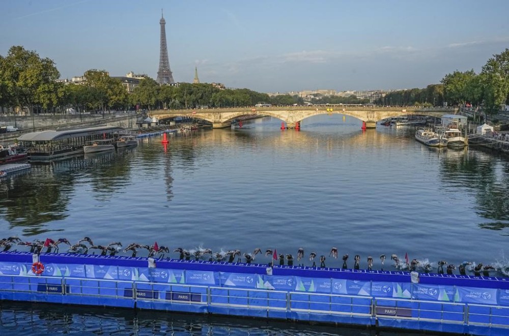 FILE - Athletes dive into the Seine River from the Alexander III bridge on the start of the first leg of the women's triathlon test event for the 2024 Paris Olympics in Paris, Aug. 17, 2023. (AP Photo/Michel Euler, File)
