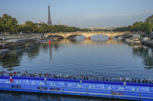 FILE - Athletes dive into the Seine River from the Alexander III bridge on the start of the first leg of the women's triathlon test event for the 2024 Paris Olympics in Paris, Aug. 17, 2023. (AP Photo/Michel Euler, File)