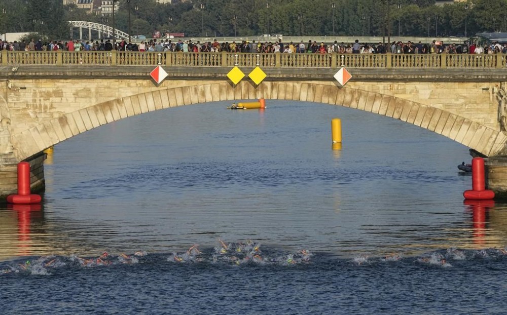 FILE - Athletes swim in the Seine river on the first leg of the women's triathlon test event for the 2024 Paris Olympics in Paris, Aug. 17, 2023. In 2024. (AP Photo/Michel Euler, File)