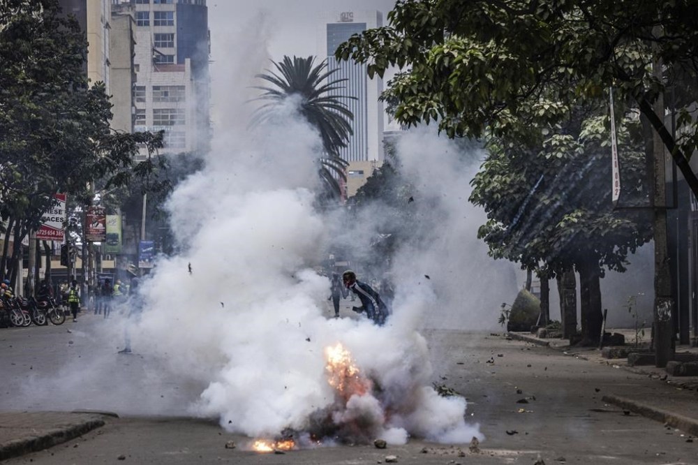 A protester runs away from tear gas fired by police in Nairobi, Kenya, Tuesday, July 16, 2024. Police in Kenya hurled tear gas canisters to break up protests on Tuesday in Nairobi and other major cities accusing the president of poor governance and calling for his resignation despite his dismissal of nearly the entire Cabinet last week. (AP Photo/Ed Ram)