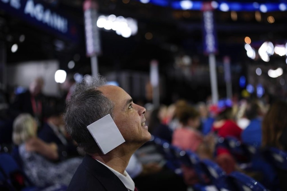 Arizona delegate Joe Neglia place a paper on his ear during the Republican National Convention Tuesday, July 16, 2024, in Milwaukee. (AP Photo/Jae C. Hong)