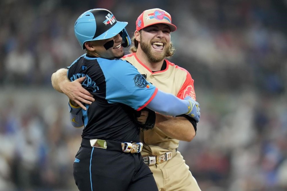 American League starting pitcher Corbin Burnes, of the Baltimore Orioles, right, hugs National League's William Contreras, of the Milwaukee Brewers, after an out on a ground ball by Contreras in the first inning during the MLB All-Star baseball game, Tuesday, July 16, 2024, in Arlington, Texas. (AP Photo/Julio Cortez)