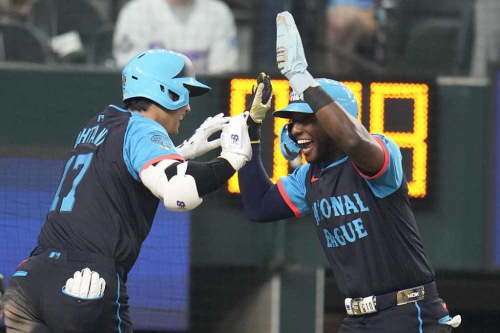 National League's Shohei Ohtani, of the Los Angeles Dodgers, left, celebrates his three-run home with Jurickson Profar, of the San Diego Padres, in the third inning during the MLB All-Star baseball game, Tuesday, July 16, 2024, in Arlington, Texas. (AP Photo/Julio Cortez)