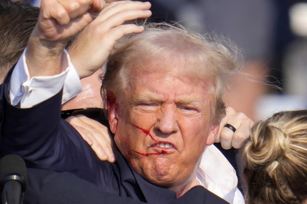 Republican presidential candidate former President Donald Trump gestures as he is surrounded by U.S. Secret Service agents as he is helped off the stage at a campaign rally in Butler, Pa., Saturday, July 13, 2024. (AP Photo/Gene J. Puskar)