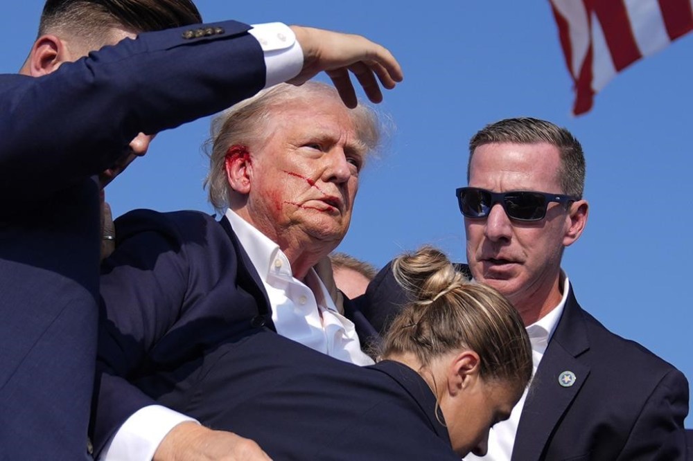 Republican presidential candidate former President Donald Trump is surrounded by U.S. Secret Service agents as he leaves the stage at a campaign rally, Saturday, July 13, 2024, in Butler, Pa. (AP Photo/Evan Vucci)