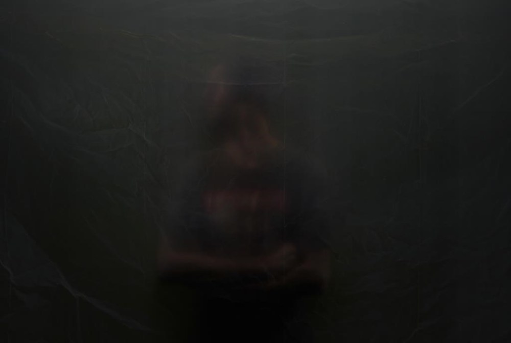 A former greenhouse worker at AppHarvest, who wishes to remain anonymous, poses for a portrait behind a sheet of plastic, Tuesday, July 9, 2024, in Morehead, Ky.