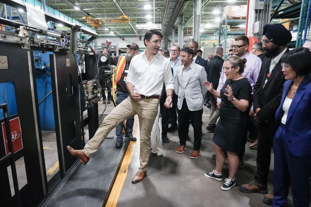 Prime Minister Justin Trudeau pretends to put his foot in a sliding door as Deputy Prime Minister and Minister of Finance, Chrystia Freeland, and Toronto Mayor Olivia Chow, look on, during a visit to a Toronto Transit Commission yard in Toronto on Wednesday, July 17, 2024. THE CANADIAN PRESS/Chris Young