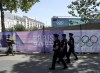 A soldier and police officers patrol by Paris 2024 Olympic banners, just nine days before the start of the Paris Olympic games, Wednesday, July 17, 2024 in Paris. (AP Photo/Aurelien Morissard)
