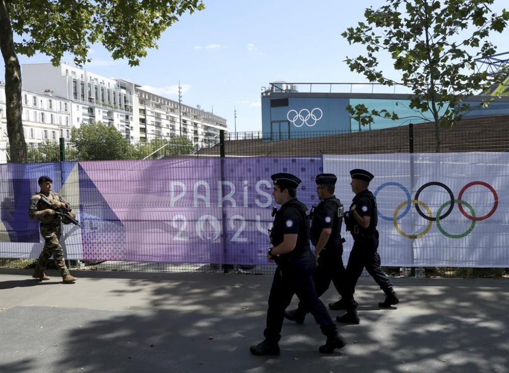 A soldier and police officers patrol by Paris 2024 Olympic banners, just nine days before the start of the Paris Olympic games, Wednesday, July 17, 2024 in Paris. (AP Photo/Aurelien Morissard)