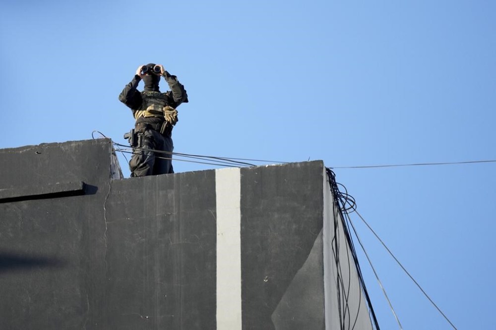 A police officer on a rooftop monitors the area during a ceremony marking the 30th anniversary of the bombing of the AMIA Jewish center that killed 85 people in Buenos Aires, Argentina, Thursday, July 18, 2024. (AP Photo/Natacha Pisarenko)