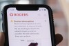 A person looks at their cell phone displaying a Rogers service interruption alert in Montreal on July 8, 2022. THE CANADIAN PRESS/Graham Hughes