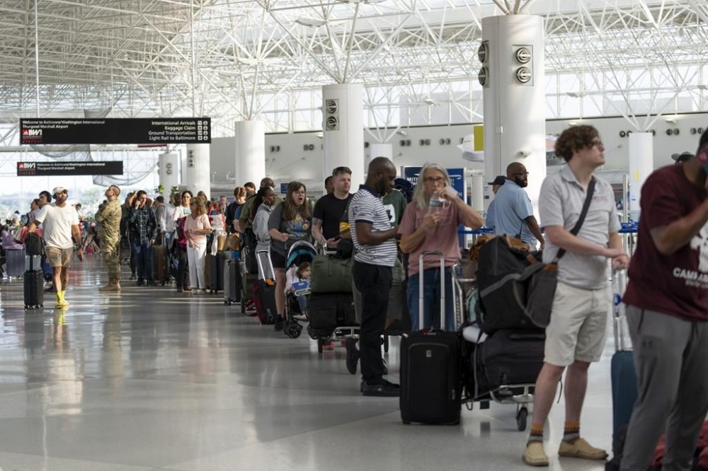 Travelers wait in line at Baltimore/Washington International Thurgood Marshall Airport in Baltimore, Friday, July 19, 2024. (AP Photo/Stephanie Scarbrough)
