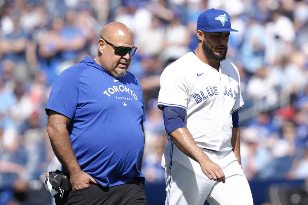Toronto Blue Jays relief pitcher Yimi Garcia walks back to the dug out with a member of the Blue Jays medical staff during ninth inning American League MLB baseball action in Toronto on June 16, 2024. THE CANADIAN PRESS/Chris Young