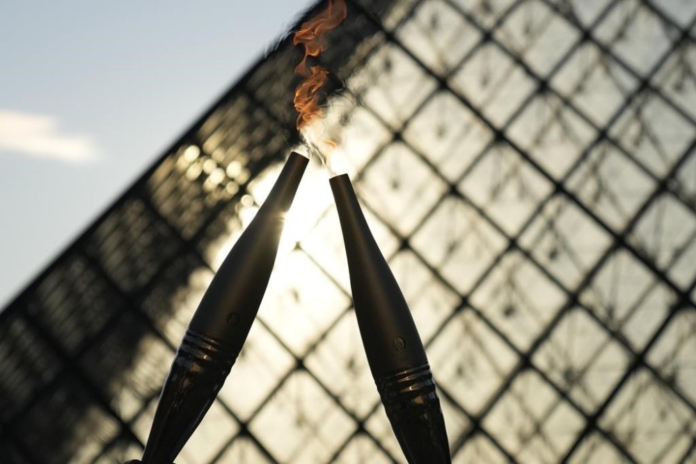FILE -The Olympic torch is seen during a relay in the courtyard of the Louvre museum Sunday, July 14, 2024 in Paris. French prosecutors say a 19-year-old man, who has made threats on social media and was suspected of wanting to target the Olympic torch relay, was sentenced to two years in prison. (AP Photo/Christophe Ena, File)