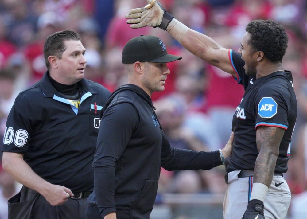 Miami Marlins' Dane Myers, right, reacts after being ejected by home plate umpire Derek Thomas, left, as manager Skip Schumaker, center, intervenes during the eighth inning of a baseball game against the Cincinnati Reds, Saturday, July 13, 2024, in Cincinnati. (AP Photo/Jeff Dean)