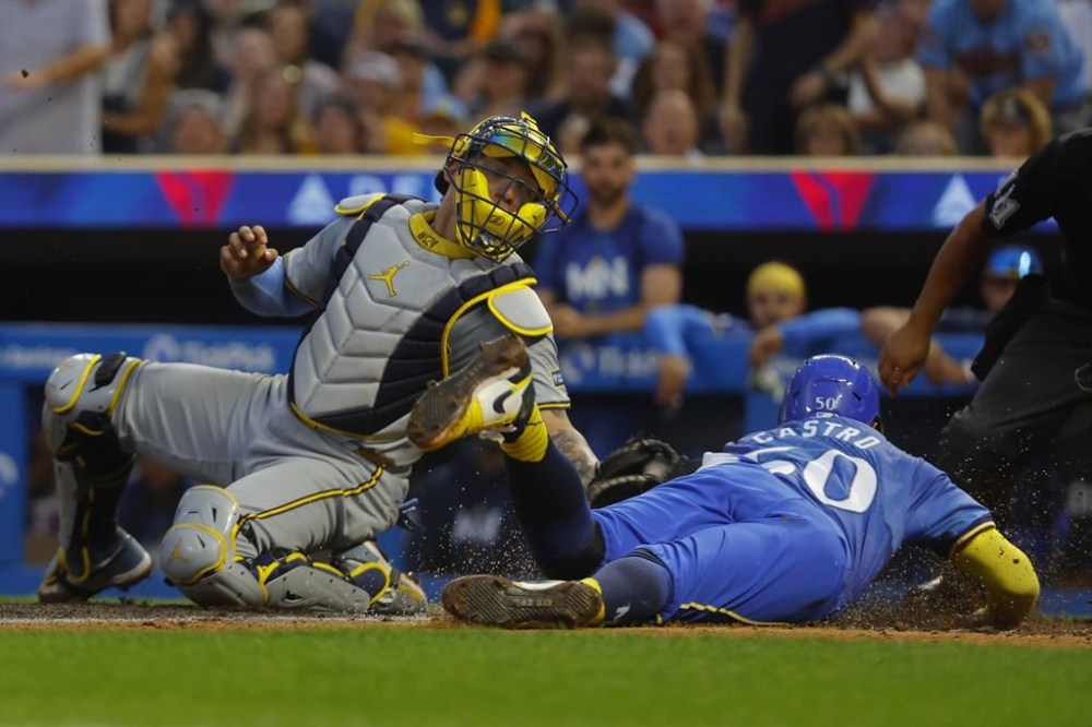Minnesota Twins' Willi Castro, right, slides into home plate past the tag of Milwaukee Brewers catcher William Contreras, left, in the eighth inning of a baseball game Saturday, July 20, 2024, in Minneapolis. (AP Photo/Bruce Kluckhohn)