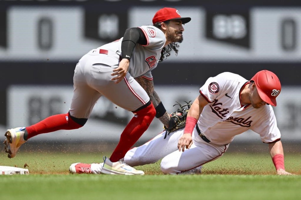 Cincinnati Reds second baseman Jonathan India, left, tags out Washington Nationals' Lane Thomas, right, who was attempting to steal second during the first inning of a baseball game Sunday, July 21, 2024, in Washington. (AP Photo/John McDonnell)