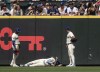 Seattle Mariners Julio Rodriguez, center, lies on the ground between right fielder Victor Robles, left, and left fielder Dylan Moore after crashing into the outfield wall during the eighth inning of a baseball game against the Houston Astros, Sunday, July 21, 2024, in Seattle. (AP Photo/Stephen Brashear)