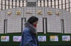 FILE - A woman walks by China's central bank, or the People's Bank of China in Beijing, Tuesday, Feb. 20, 2024. China's central bank cut key interest rates in a surprise move Monday, July 22, 2024 aimed at injecting new life into its ailing property sector, while the ruling Communist Party released details of a top-level meeting focused on strategies for revving up the slowing economy. (AP Photo/Andy Wong, File)