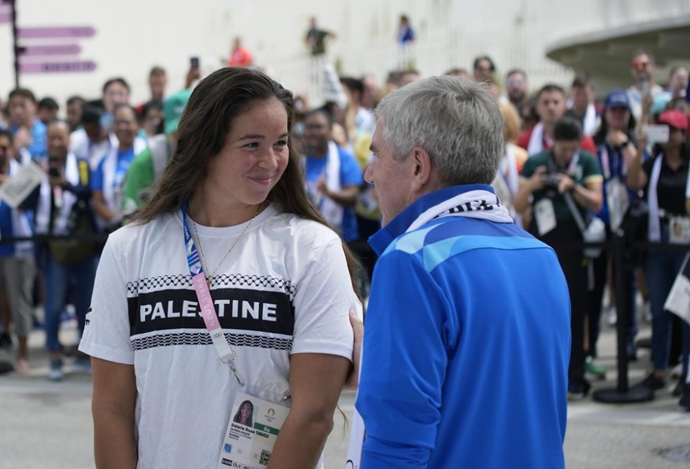 IOC President Thomas Bach talks to Palestinian athlete Valerie Rose Tarazi, left, after she signed the Peace Monument at the Olympic Village, head of the 2024 Summer Olympics, Monday, July 22, 2024, in Paris, France. (AP Photo/David Goldman)