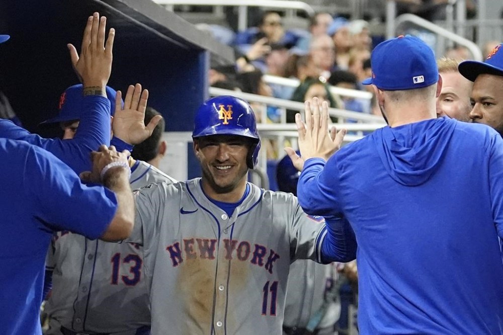 New York Mets' Jose Iglesias (11) is congratulated after scoring on a sacrifice fly hit by Jeff McNeil during the fourth inning of a baseball game against the Miami Marlins, Monday, July 22, 2024, in Miami. (AP Photo/Lynne Sladky)