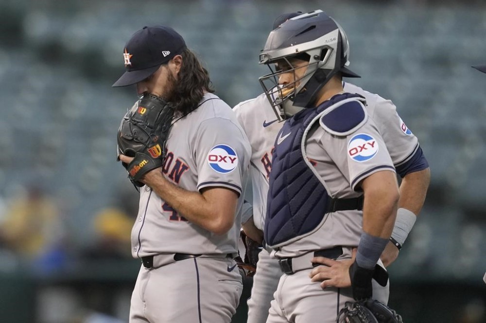 Houston Astros pitcher Spencer Arrighetti, left, reacts next to catcher Yainer Diaz, right, and shortstop Jeremy Peña, rear, during a meeting on the mound in the fourth inning of a baseball game against the Oakland Athletics in Oakland, Calif., Monday, July 22, 2024. (AP Photo/Jeff Chiu)