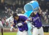 Colorado Rockies' Charlie Blackmon, back, douses Ezequiel Tovar after his walkoff RBI single off Boston Red Sox relief pitcher Chase Anderson in the 12th inning of a baseball game Monday, July 22, 2024, in Denver. (AP Photo/David Zalubowski)