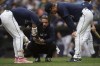 Seattle Mariners' J.P. Crawford, left, is checked by a team trainer, center, and manager Scott Servais, right, after getting hit by a pitch during the first inning of a baseball game against the Los Angeles Angels, Monday, July 22, 2024, in Seattle. (AP Photo/Stephen Brashear)