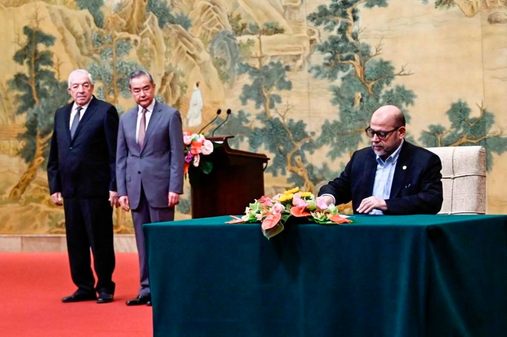 Mussa Abu Marzuk, a senior member of Hamas, right, signs a document as China's Foreign Minister Wang Yi, second left, and Mahmoud al-Aloul, vice chairman of Fatah, look on during an event hosting the Palestinian factions to meet at the Diaoyutai State Guesthouse in Beijing, Tuesday, July 23, 2024. (Pedro Pardo/Pool Photo via AP)