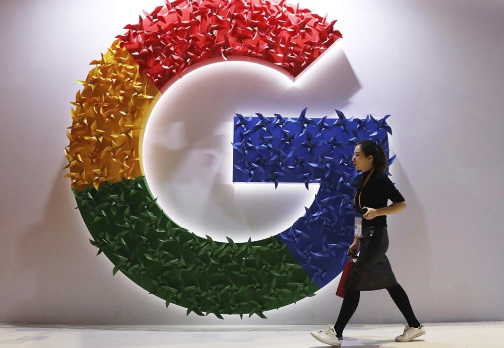 FILE - In this Nov. 5, 2018 file photo, a woman walks past the logo for Google at the China International Import Expo in Shanghai. Google is dropping plans to eliminate cookies from its Chrome web browser, making a sudden U-turn on four years of work to phase out the technology that tracks users for ad purposes. (AP Photo/Ng Han Guan, File)