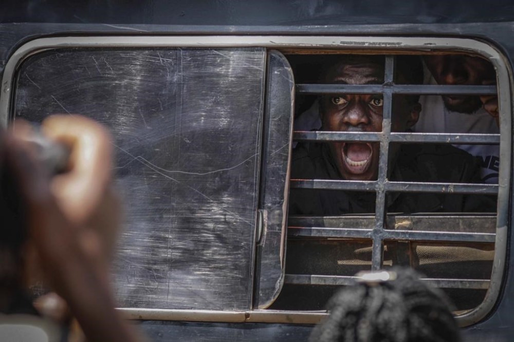 A protester screams as he is carried away with others after being arrested by military police during the anticorruption protest in Kampala, Uganda, Tuesday, July 23, 2024. Ugandan security forces on Tuesday arrested dozens of people who tried to walk to the parliament building to demonstrate against high-level corruption in protests that authorities say are unlawful. (AP Photo/Hajarah Nalwadda)