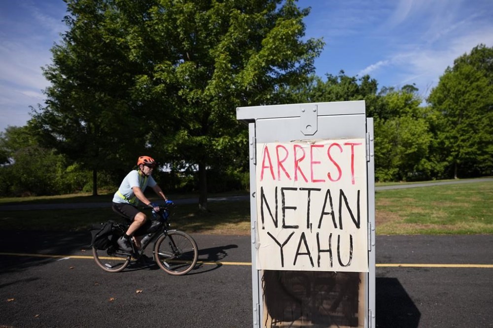 A man rides his back near The Watergate Hotel, Tuesday, July 23, 2024, in Washington. Israeli Prime Minister Benjamin Netanyahu is in Washington this week to address Congress on Wednesday and is expected to meet with President Joe Biden on Thursday. (AP Photo/Matt Slocum)