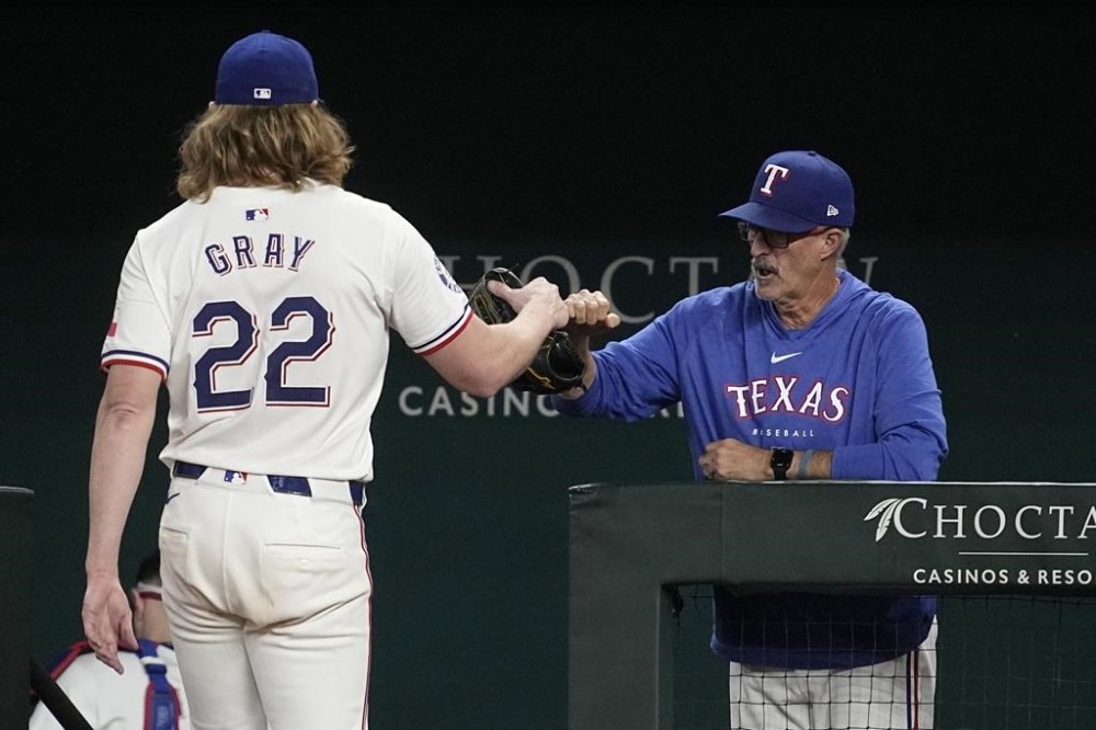 Texas Rangers' Jon Gray is greeted at the dugout entrance by pitching coach Mike Maddux after Gray threw to the Chicago White Sox in the sixth inning of a baseball game, Tuesday, July 23, 2024, in Arlington, Texas. (AP Photo/Tony Gutierrez)