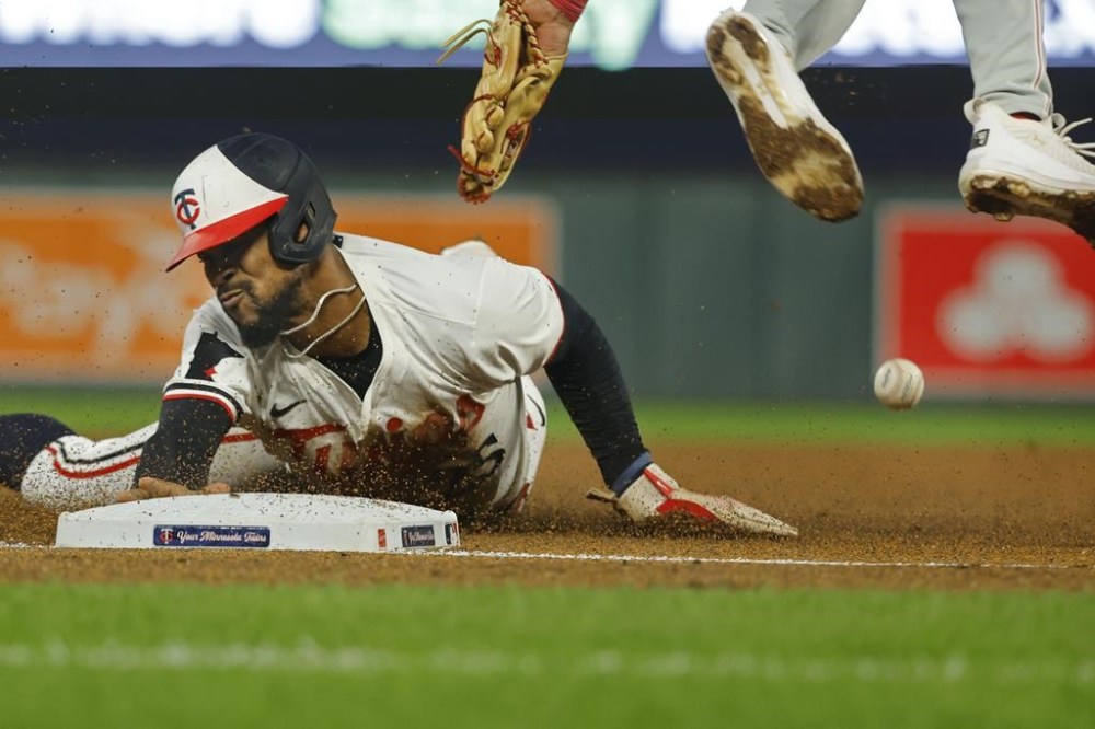 Minnesota Twins' Byron Buxton advances to third base on a wild pitch as Philadelphia Phillies third baseman Alec Bohm tries to handle the throw in the eighth inning of a baseball game, Tuesday, July 23, 2024, in Minneapolis. (AP Photo/Bruce Kluckhohn)