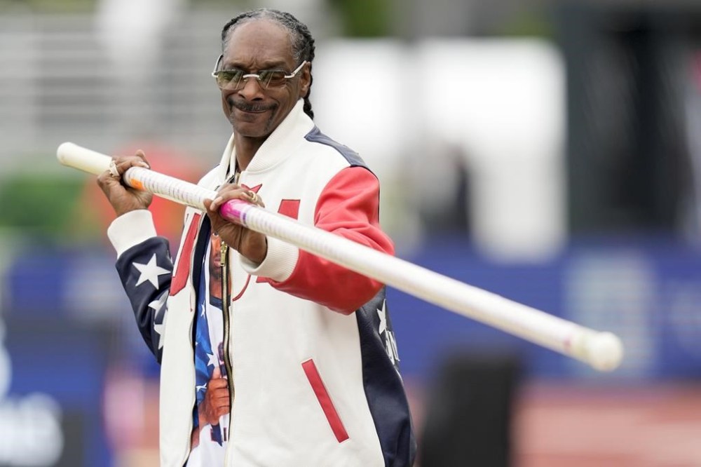FILE - Snoop Dogg gets a pole vaulting lesson during the U.S. Track and Field Olympic Team Trials on June 23, 2024, in Eugene, Ore. Snoop will be one of the final torchbearers of the Olympic flame ahead of the Games’ opening ceremony Friday, July 26. (AP Photo/Charlie Neibergall, File)