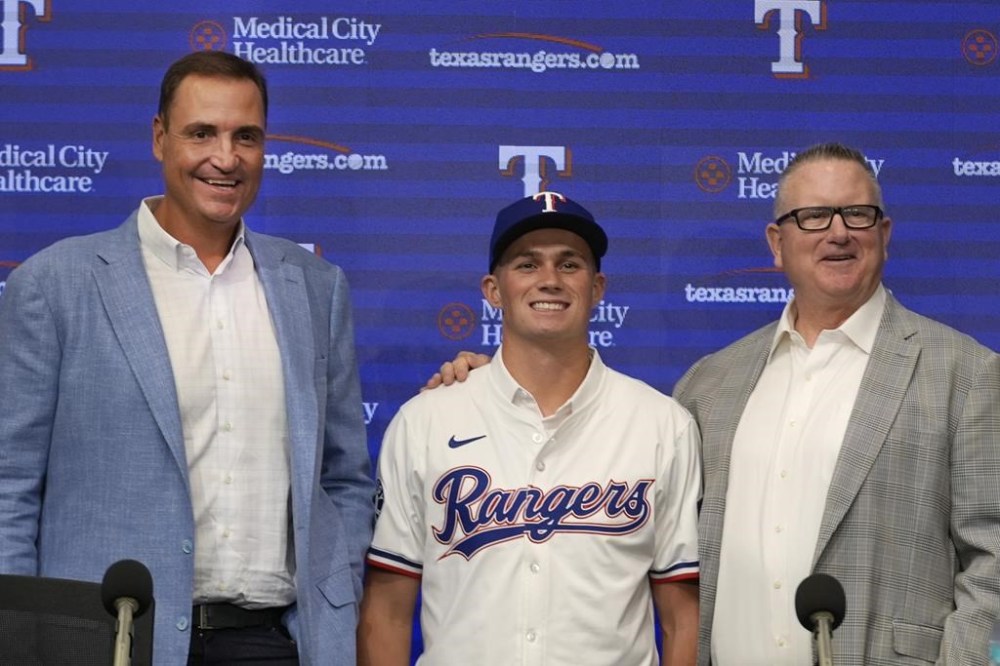 Texas Rangers first round draft pick catcher Malcolm Moore, center, smiles for photos with Rangers general manager Chris Young, left, and scouting director Kip Fagg after a news conference in Arlington, Texas, Wednesday, July 24, 2024. (AP Photo/LM Otero)